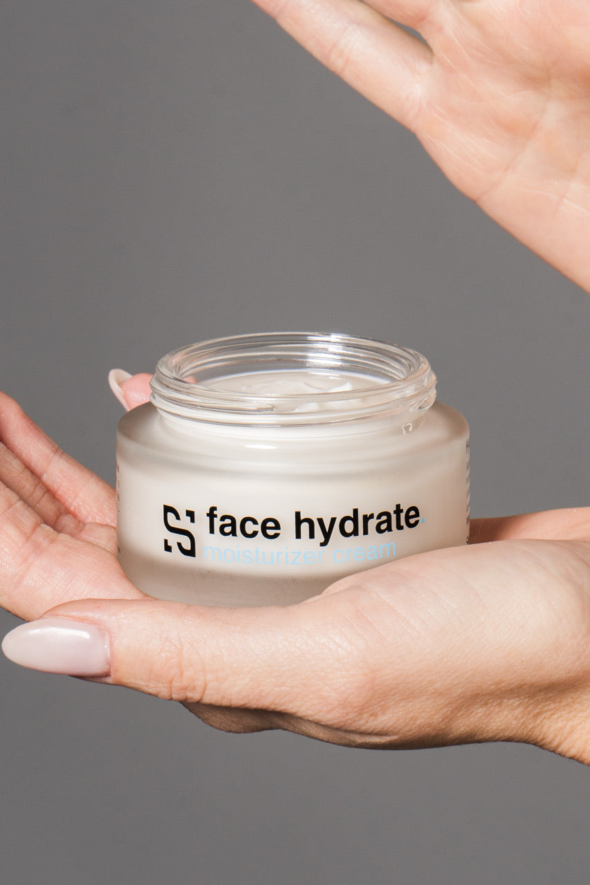 mani di una ragazza che sorreggono una confezione di crema cosmetica idratante al cannabidiolo face hydrate di sensitiva